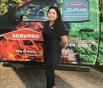 Female employee with dark hair standing infront of SERVPRO vehicle