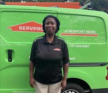 Female employee standing in front of SERVPRO vehicle