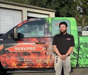 Male employee with brown hair standing in front of SERVPRO truck