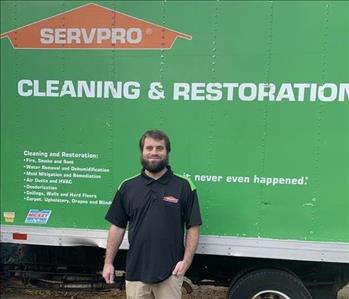 Male employee with brown hair standing in front of SERVPRO truck